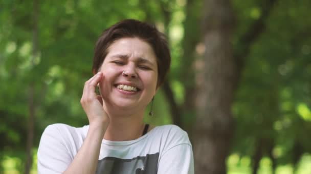 lustige brünette Frau lacht und hebt ihre Hand zu ihrem Gesicht in einem Wald in slo-mo - Filmmaterial, Video
