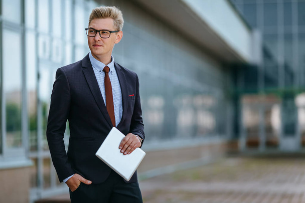 Happy smiling businessman with digital tablet. Portrait of a Male executive manager in trendy clothes with tablet PC in hand on background of office building. Modern technology concept - Foto, Imagen