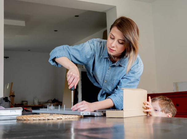 woman with screwdriver instaling a furniture at home personally - Foto, afbeelding