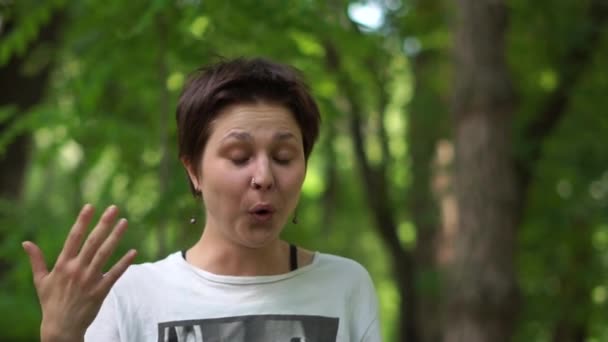 tief berührte brünette Frau lächelt und winkt ihre Hand in einem Wald in slo-mo - Filmmaterial, Video