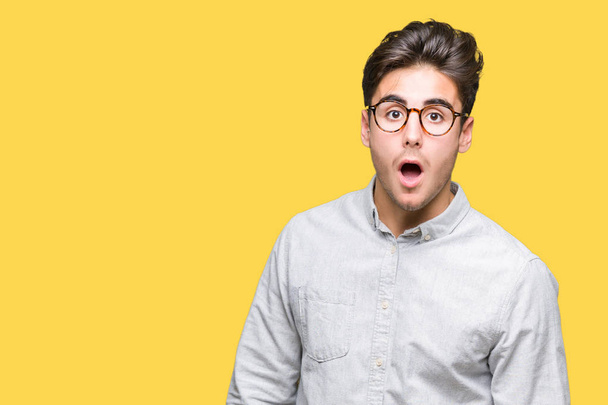 Young handsome man wearing glasses over isolated background In shock face, looking skeptical and sarcastic, surprised with open mouth - Photo, Image