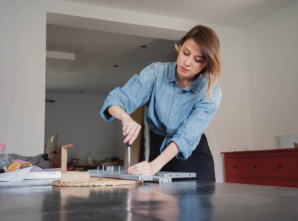 woman with screwdriver instaling a furniture at home personally - Photo, Image