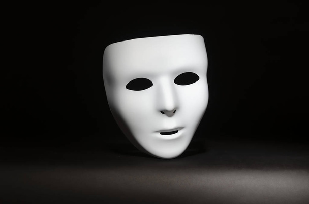 μια κενή, χωρίς αισθήματα μάσκα μασκέ επισημαίνεται σε ένα μαύρο φόντο  - Φωτογραφία, εικόνα