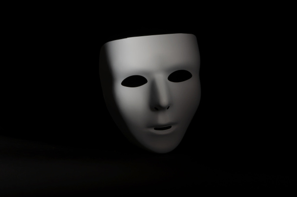 egy üres, érzelemmentes maskara maszk van kiemelve szemben egy éles fekete háttér  - Fotó, kép