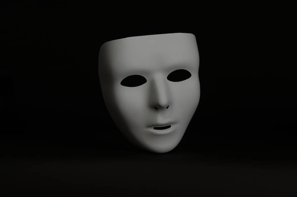 un masque de mascarade vide et sans émotion est mis en évidence sur un fond noir
  - Photo, image