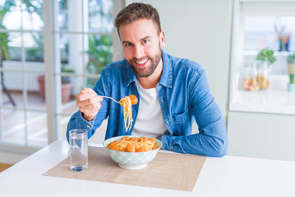 Przystojny mężczyzna jedzenie makaron z sosem pomidorowym w hom i klopsiki - Zdjęcie, obraz