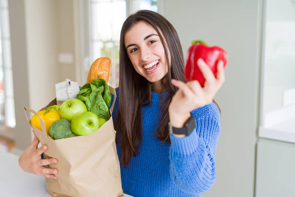 Fiatal gyönyörű nő mosolyogva kezében papír táska tele fűszeres - Fotó, kép