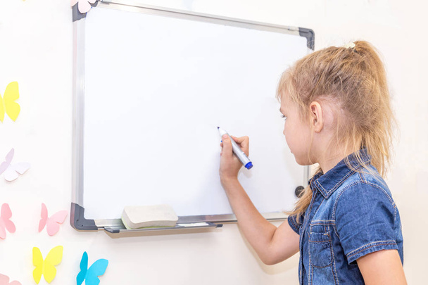 Little girl writing on empty whiteboard with a marker pen - Zdjęcie, obraz