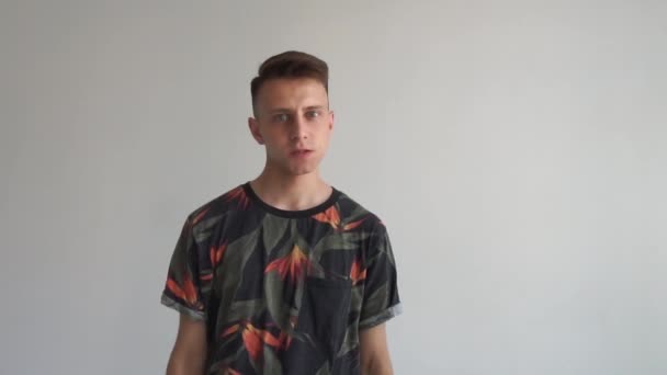 Giovane uomo dai capelli biondi in piedi con una faccia fumante in uno studio bianco a rallentatore
 - Filmati, video
