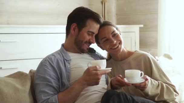 Lovely couple in love talking sitting on couch drinking tea - Video, Çekim