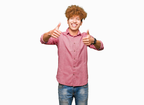 Fiatal jóképű üzletember afro haj jóváhagyása során pozitív gesztus kézzel, remek fel mosolyogva és boldog a siker. Néz a kamerába, győztes gesztus. - Fotó, kép