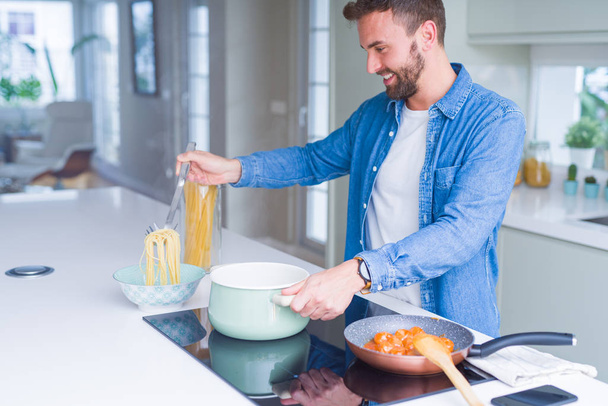 Handsome man cooking pasta at home - Zdjęcie, obraz