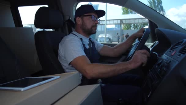 Kézbesítő a sapka ellenőrzése útvonalon ül az autóban - Felvétel, videó