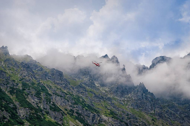 Tatran kansallispuisto, Puola. 17. elokuuta 2019. Punainen helikopteri lentää vuorten yli
 - Valokuva, kuva
