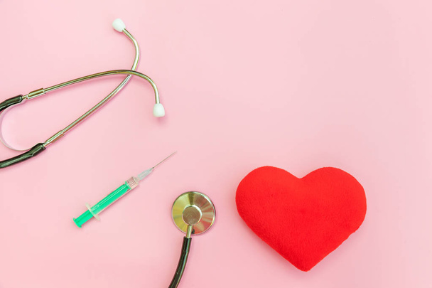 Medicine equipment stethoscope or phonendoscope syringe and red heart isolated on trendy pastel pink background - Photo, image