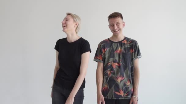 Gelukkige jonge kerel en hip Chick staan en lachen samen in een studio in slo-mo - Video