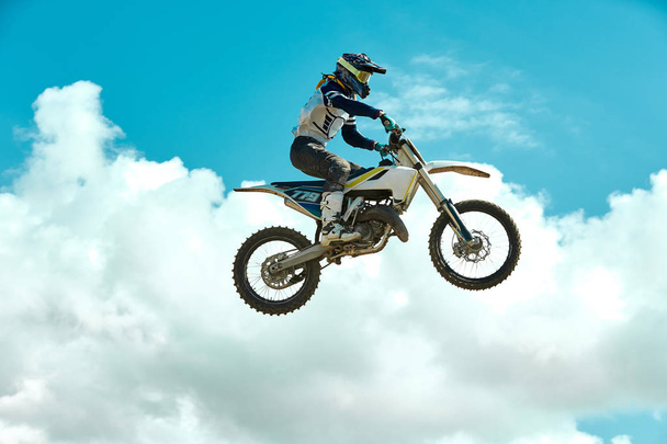 Pilota su moto dirtbike motocross cross-country in volo, salta e decolla sul trampolino contro il cielo. Concetto riposo estremo attivo
. - Foto, immagini