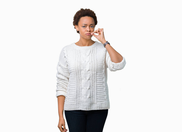 Linda jovem afro-americana vestindo suéter sobre fundo isolado boca e lábios fechados como zip com os dedos. Segredo e silencioso, tabu falando
 - Foto, Imagem