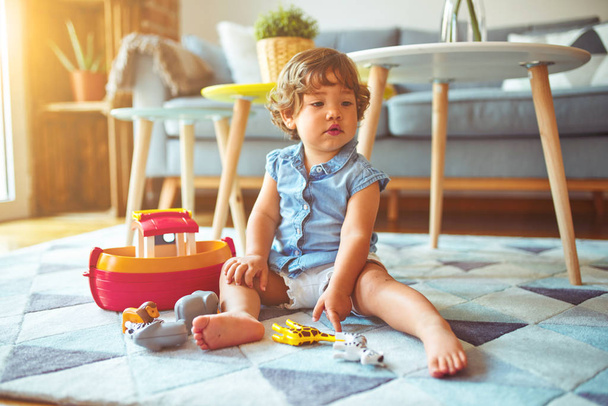 Hermosa niña jugando con juguetes en la alfombra
 - Foto, Imagen