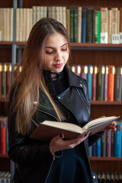 Kaunis teini koulutyttö lukemassa kirjaa kirjastossa
 - Valokuva, kuva