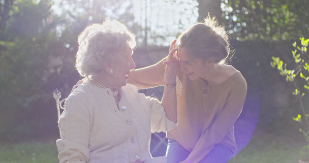 孫娘訪問、外の庭でおばあちゃんを抱きしめ、バックライトの太陽。多世代の女性は一緒に抱くのが大好きです。白髪高齢おばあちゃん女性。愛情,一体感,思いやり,愛情 - 映像、動画