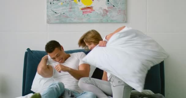 Young mixed couple start a pillow fight in bedroom - Séquence, vidéo