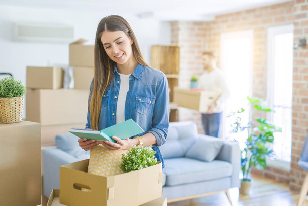 Young couple moving to a new home, beautiful woman smiling moving cardboard box - Photo, Image