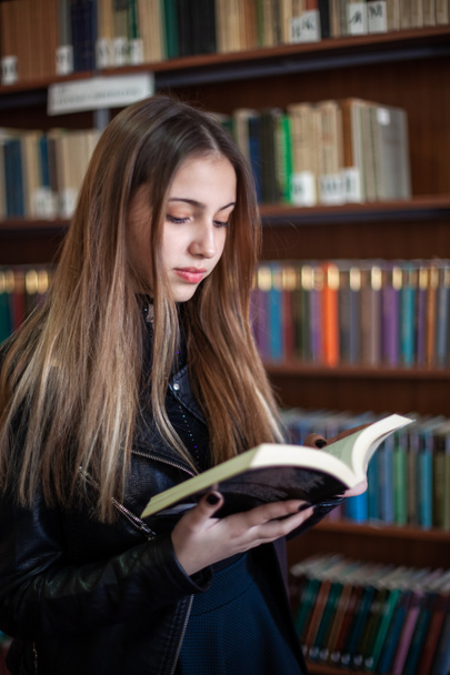 Piękna uczennica nastolatek czytania książki w bibliotece - Zdjęcie, obraz