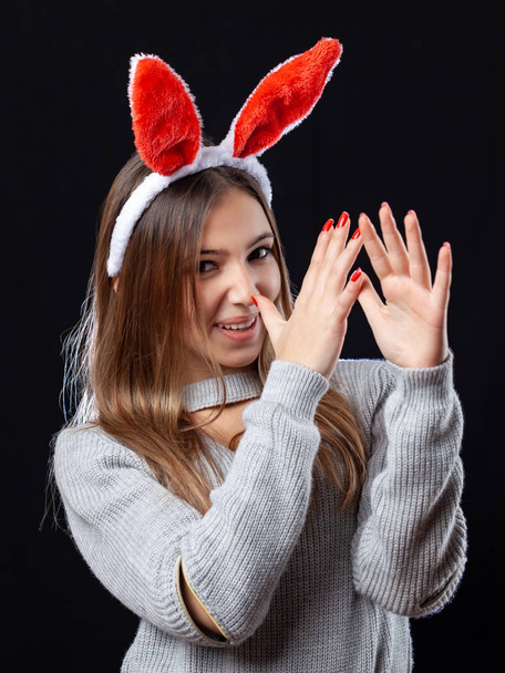 Hermosa chica con accesorio de conejo posando sobre fondo negro
. - Foto, Imagen