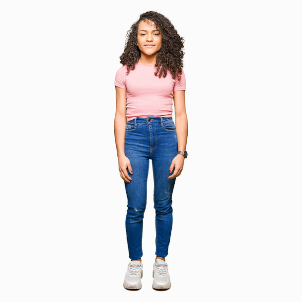 Young beautiful woman with curly hair wearing pink t-shirt Relaxed with serious expression on face. Simple and natural looking at the camera. - Photo, image