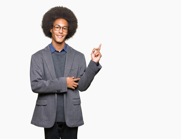 Young african american business man with afro hair wearing glasses with a big smile on face, pointing with hand and finger to the side looking at the camera. - Foto, Bild