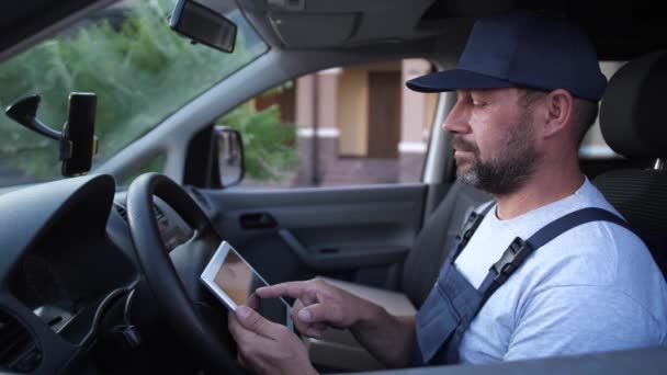 車の中でタブレット上の注文をチェックする配達人 - 映像、動画