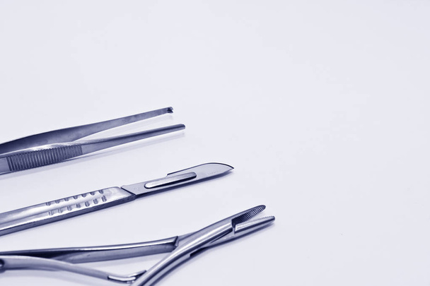 Instrumentos quirúrgicos aislados en el fondo blanco se centran en la cuchilla de bisturí
 - Foto, Imagen