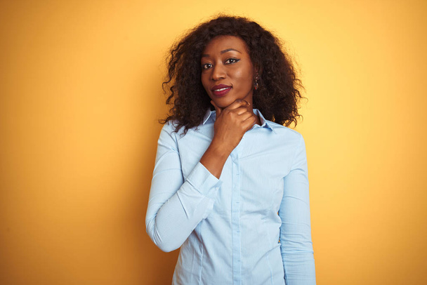 Африканская американская бизнесвумен в элегантной рубашке на изолированном желтом фоне, уверенно смотрящая в камеру со скрещенными руками и поднятой на подбородок улыбкой. Мысли позитивно
. - Фото, изображение