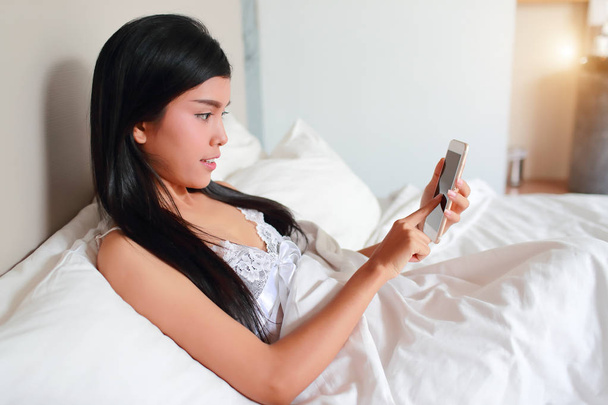 mulher jovem e sexy usando telefone celular na cama
 - Foto, Imagem