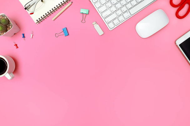 Top weergave of platte lay roze pastel Office Bureau met computer, kantoorbenodigdheden en koffie kopje - Foto, afbeelding