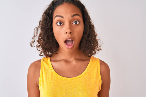 Young brazilian woman wearing t-shirt standing over isolated white background scared in shock with a surprise face, afraid and excited with fear expression - Photo, Image