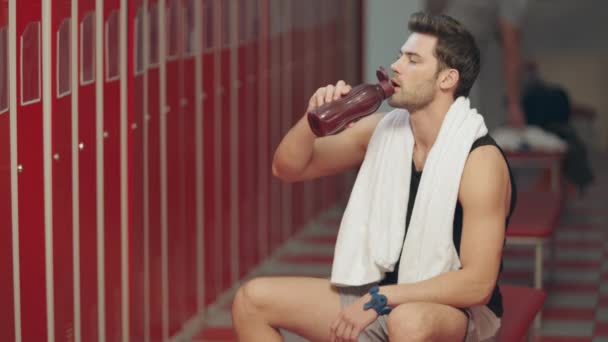 Уставший спортсмен пьет воду в раздевалке
. - Кадры, видео