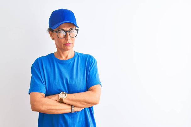 Senior deliverywoman wearing cap and glasses standing over isolated white background skeptic and nervous, disapproving expression on face with crossed arms. Negative person. - Foto, Imagem