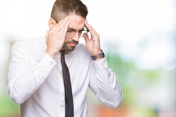 Young handsome business man wearing glasses over isolated background with hand on head for pain in head because stress. Suffering migraine. - Photo, Image