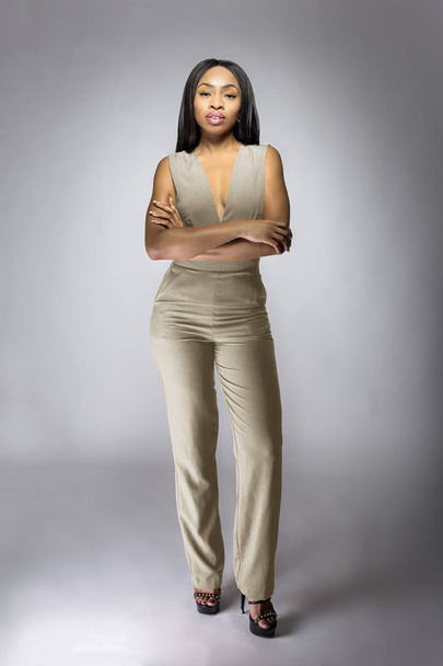 Beautiful black African American fashion model posing with humus grey or khaki clothing in a studio for fall collection catalog.  She is confidently showing the sleeveless top and matching pants.   - Foto, immagini