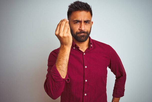 Young indian man wearing red elegant shirt standing over isolated grey background Doing Italian gesture with hand and fingers confident expression - Foto, afbeelding
