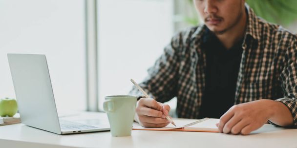 Motivated male freelance writing his idea on notebook - Photo, image