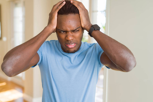 Handsome african american man wearing casual t-shirt suffering from headache desperate and stressed because pain and migraine. Hands on head. - Photo, image
