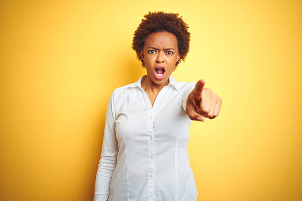 Africká americká obchodní žena přes izolované žluté pozadí ukazující na kameru nelibě a frustrovanou, rozzlobená a rozzuřený - Fotografie, Obrázek