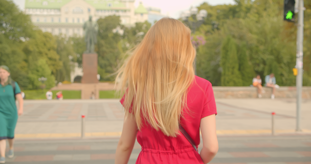 Primo piano vista posteriore ritratto della giovane bionda dai capelli lunghi bella strada di attraversamento femminile in città urbana all'aperto
 - Filmati, video
