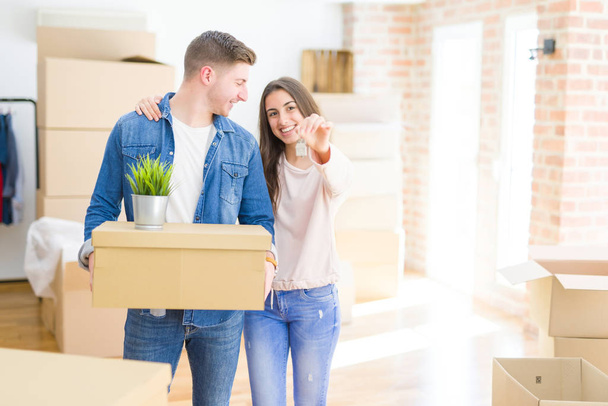 Beautiful young couple hugging in love and showing keys of new house, smiling happy moving to a new apartment - Photo, Image