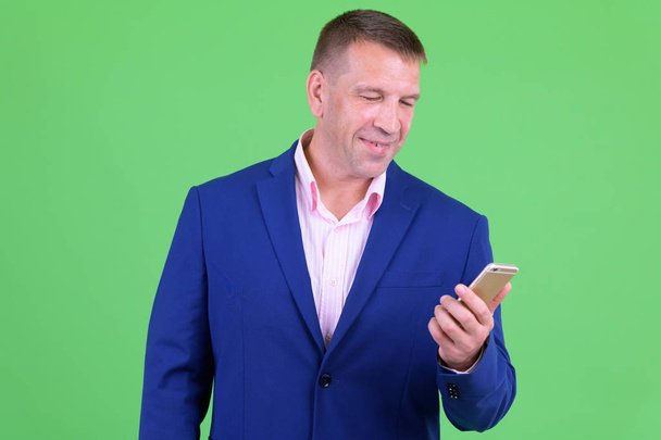 Happy mature macho businessman in suit using phone - Photo, Image