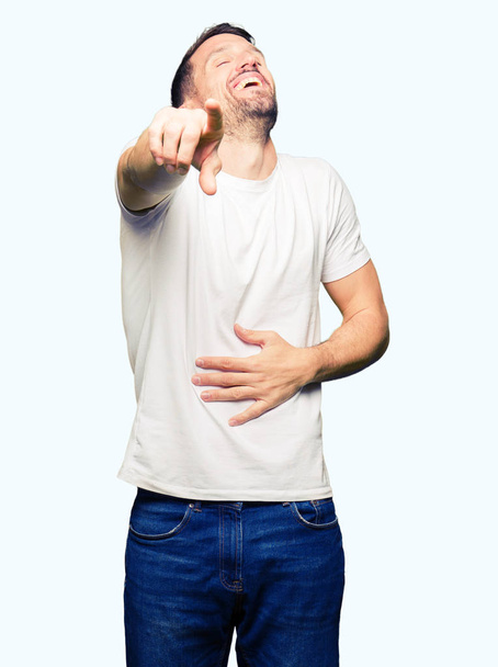 Hombre guapo vistiendo una camiseta blanca casual riéndose de ti, señalando a la cámara con la mano sobre el pecho, expresión de vergüenza
 - Foto, imagen
