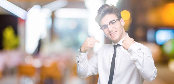 Молодий бізнесмен в окулярах над ізольованим тлом виглядає впевнено з посмішкою на обличчі, вказуючи на себе пальцями гордим і щасливим
. - Фото, зображення